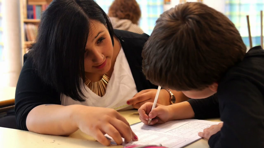 Voluntaria acompañando a un niño en sus tareas escolares